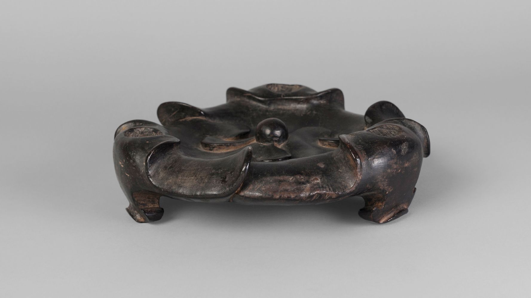 A Chinese hardwood tripod censer stand, 18th century, carved as lotus pads, with three ruyi-shaped