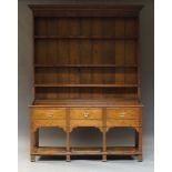 A George III oak dresser, with boarded plate rack above three drawers and pot board, on square feet,