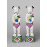 A pair of Chinese porcelain famille rose figures of boys, early 19th century, each modelled