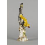 A Sitzendorf porcelain model of a yellow bird, late 19th century, modelled perching on a tree