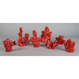 A collection of Chinese red coral specimens, 20th century, variously carved with mythical creatures,