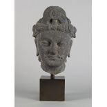A Ghandaran style fragmentary schist head of a Bodhisattva, wearing an ornate hat, with serene