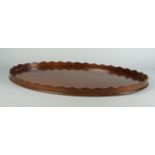 A large oval mahogany tray, late 19th/early 20th century, with a wavy edged gallery inset with