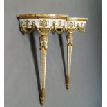 A pair of Louis XVI style white painted and parcel gilt corner console tables with marble tops, late