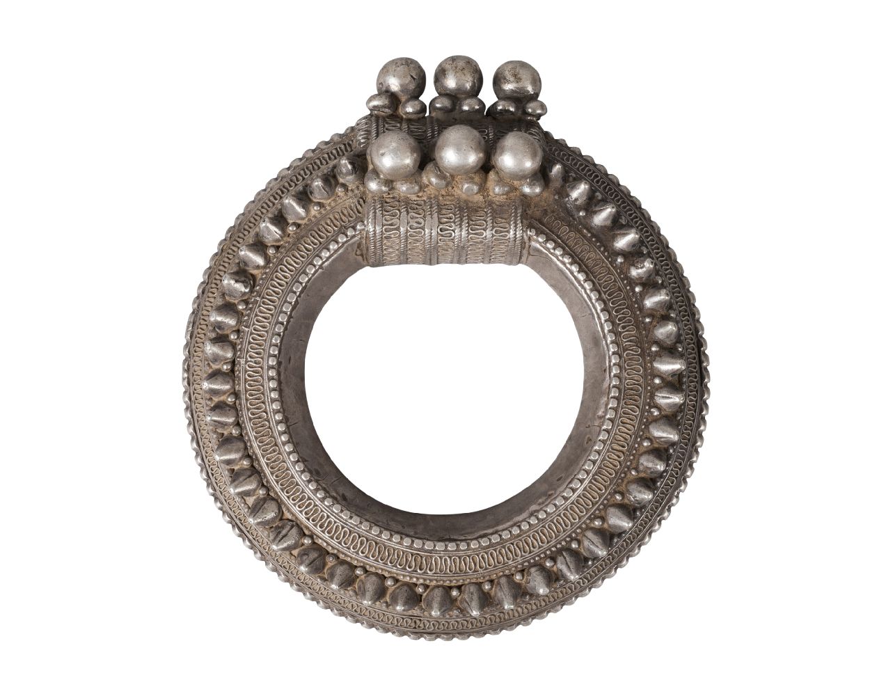 A Nepalese white metal bangle, 19th century, studded and with filigree decoration, 15cm diameter