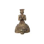A Nepalese bronze figural lamp, 19th century, modelled with a kneeling man praying, behind oil