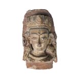 A Tibetan terracotta head, 19th century, modelled as the head of Shiva, later painted, 23cm high