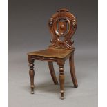 A Victorian mahogany hall chair, the pierced back, with carved crest and scrolling motifs, raised on