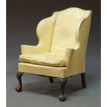 A George III style wingback armchair, 19th Century, upholstered in yellow floral fabric, on front