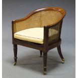 A Regency mahogany and caned bergere tub chair, the curved back with cane work, above moulded seat