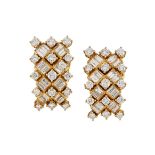 A pair of diamond earclips, each designed as a rectangular domed panel set with a baguette diamond