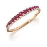 A late 19th century French, gold, ruby and diamond bangle, the hinged half-hoop set with a graduated