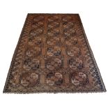 An Afghan carpet with three rows of octagons, early 20th Century, in a rust coloured field, with