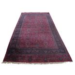A Kirman carpet with all over design in cerise coloured field, indigo main border and end sections