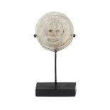 A Roman glass theatre token depicting a theatre mask, 1st-3rd century AD, on stand, 3cm. diam.