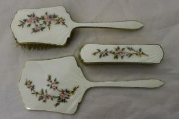 A silver and enamel mirror, hairbrush and clothes brush,