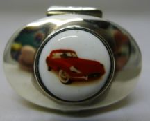 A silver pill box depicting a car