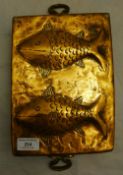 An Arts & Crafts copper fish decorated twin handled pan