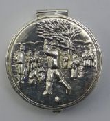 A silver pill box depicting a golfing scene