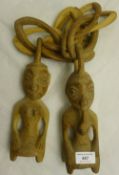 A pair of carved wooden Yoruba Ere Ibeji twin figures interlinked by a wooden chain