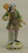 A small porcelain figure of a man in a green coat