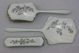 A silver and enamel mirror, hairbrush and clothes brush,