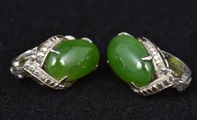 A pair of 14K white gold and jade ear clips Each with a claw set cabochon stone. Each 2.25 cm high.