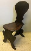 A George III mahogany hall chair The shaped back above the dished solid seat,