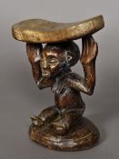 An African tribal carved wooden headrest Of typical bowed form, with female figural supports,