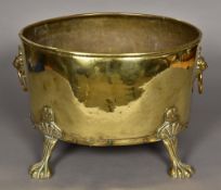 A riveted brass log bin Of oval form, with twin lion mask and ring handles,