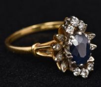 An 18 ct gold diamond and sapphire cluster ring Centrally set with a facet cut sapphire surrounded