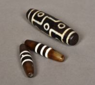 Three Tibetan etched agate Dzi beads Typically decorated. The largest 8.5 cm long.