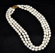 A three strand baroque pearl necklace Set with a 15 ct gold clasp. Approximately 42.5 cm long.