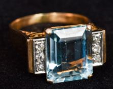 An unmarked 18 ct gold aquamarine and diamond ring The claw set facet cut aquamarine flanked by