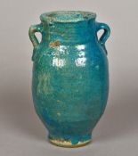 An antique Persian twin handled pottery vase With allover turquoise glaze. 27 cm high.