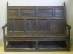 A 17th century carved oak settle The panelled back with turned finials and carved with serpents and