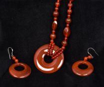 A cornelian bead necklace Set with a pierced roundel drop;