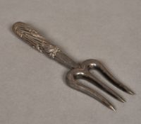 A Japanese silver trident fork The handled worked with aquatic plants, signed. 17.5 cm long.