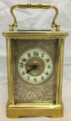 A 19th century brass cased carriage clock The scroll engraved silvered front panel centred with a