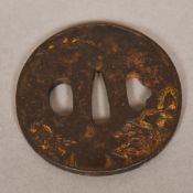 A Japanese cast tsuba Worked in gilt wi