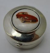 A silver pill box depicting a car