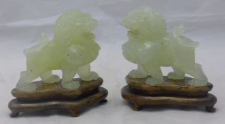 A pair of carved jade dogs-of-fo on wooden stands