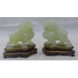 A pair of carved jade dogs-of-fo on wooden stands