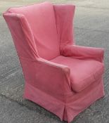 An upholstered wing armchair with salmon cover