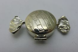 A silver pill box in the form of a sweet