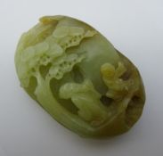 A Chinese carved green and russet jade pebble,