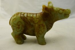 A carved green and russet jade bull with archaistic incised decoration