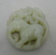 A Chinese carved jade roundel worked with a mythical beast atop an elephant