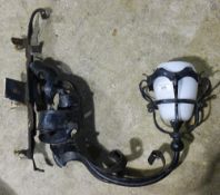 A wrought iron wall sconce with opaline glass shade