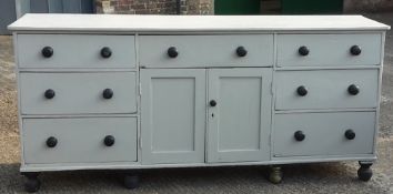 A large Victorian painted pine dresser base with seven drawers and two cupboard doors